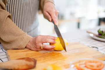 Close-up image of a woman slicing a lemon, preparing ingredients, and cooking in the kitchen. - Powered by Adobe