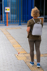 An elderly blind woman goes to a button to call help for people with disabilities. Vertical photo. 