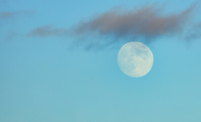 Moon with clouds on a blue gloomy sky, close-up. Beautiful background, beautiful landscape