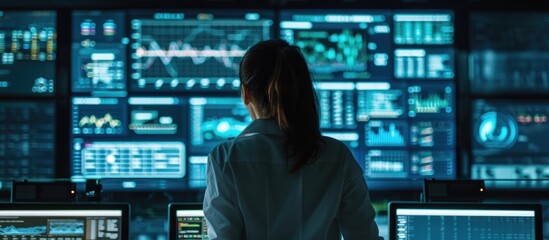 Rear view of female data scientist analyzing information on big digital screen in monitoring office. Diverse employees working for big data company.