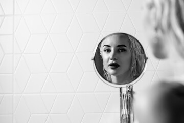 Portrait of a young beautiful blonde girl in a vintage style bathroom. Black and white photo.