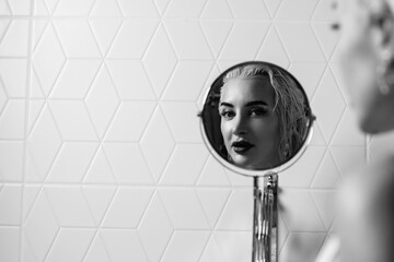 Portrait of a young beautiful blonde girl in a vintage style bathroom. Black and white photo.
