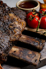 grilled pork ribs with french fries and vegetables on a wooden board