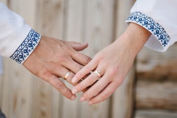 Engagement. Bride and groom wearing embroidered dress and shirts hold hands together closeup. The...