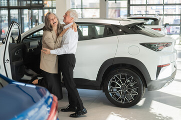 Fototapeta na wymiar Mature Caucasian couple hugging with happiness while buying a new car. 