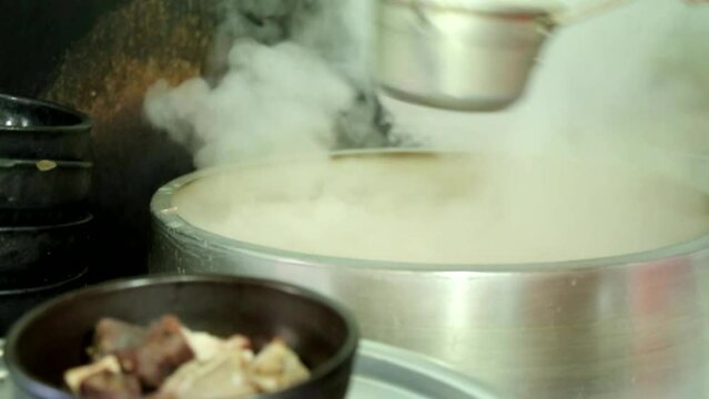 커다란 가마솥에 고기를 삻아낸 육수를 순댓국 뚝배기에 국자로 담는 
