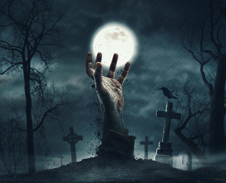 Zombie rising from the grave in the cemetery