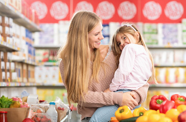 Mother and child doing grocery shopping together at the supermarket