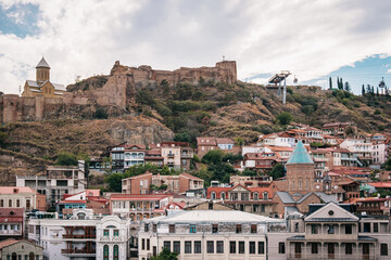 Fototapeta premium View on the Narikala fortress wall, the Tbilisi ropeway and the blue roof of the bell tower of Saint George's church in Kala, Tbilisi old town, Georgia