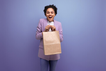 young pretty cute hispanic business woman with curly hair in a lilac jacket received delivery in an...