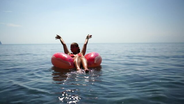 woman floats on an inflatable donut mattress. Happy woman relaxing and enjoying family summer travel holidays travel on the sea.
