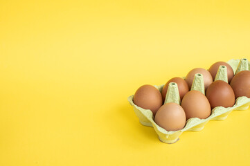 Part of a recycling tray with brown chicken eggs in a tray on a yellow background