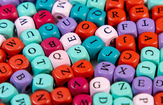 Blocks spell with different letters and colors. Image for decoration, ornament with many wooden cubic beads with selective focus