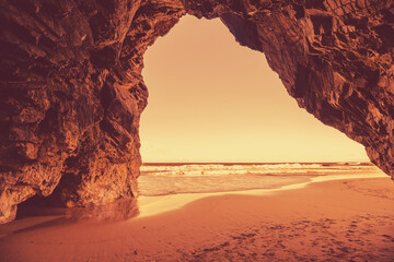Rocky seascape in the evening. View of the sea from the cave. A golden sunset on the beach. Adraga...