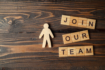 Wooden figures and wooden cubes with Join Our Team letters on a wooden table