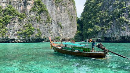 Small wooden tourist boat on a tropical island and clear green water.