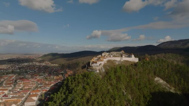 aerial orbit view of rasnov fortress with rasnov city on background in romanian carpathian mountains