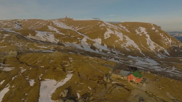 aerial view over wooden cabin  on top of the mountain with costila radio relay and varful omu on background