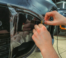 A car wrapping specialist applies a polyurethane film to the car. Selective focus. PPF protective...