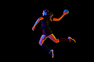 Fototapeta na wymiar Talented handball player, female sportsman practicing techniques, capturing intensity of sport against black background in neon light. Concept of hobby, movement, dynamic, lifestyle, championship. Ad