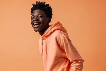 Obraz premium African American happy teenage boy wearing hoodie on peach background