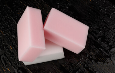 Melamine sponge on a black wet background. Beautiful drops of water around a melamine sponge.