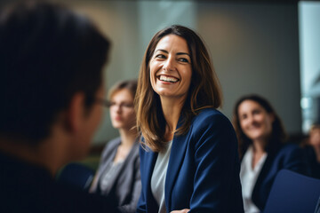 A woman in a group smiling at a woman meeting at a conference room, in the style of artistic reportage, back button focus, light amber and indigo, viennese actionism, focus on joints/connections, shap - obrazy, fototapety, plakaty