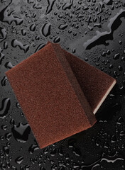 Melamine sponge on a black wet background. Beautiful drops of water around a melamine sponge.
