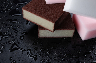 Melamine sponge on a black wet background. Beautiful drops of water around a melamine sponge.