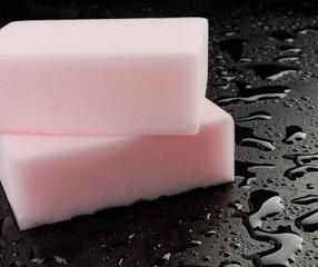 Melamine sponge on a black wet background. Beautiful drops of water around a melamine sponge.