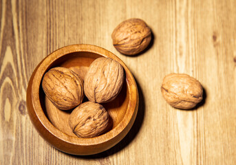 Walnuts in a wooden bowl on a wooden background. Toned. copy space, top view