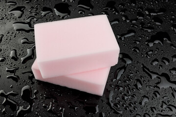 Melamine sponge on a black wet background. Beautiful drops of water around a melamine sponge.