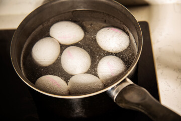 eggs are boiling in water in black stewpot close-up