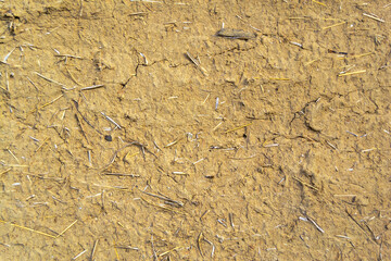An image of the texture of a clay wall. Rough, relief surface. Small cracks and scattered stones. Template for interior design, websites or promotional materials. Horizontal image.