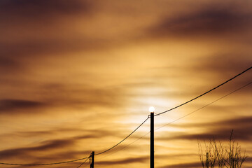 Sun on an electric pole before sunset. Concept of lack of electricity, energy crisis. Mystical...
