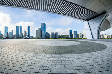 Round square floor and pedestrian bridge with modern buildings under blue sky