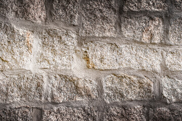 Fototapeta premium Old stone wall background. Closeup front view of dark stone wall texture.