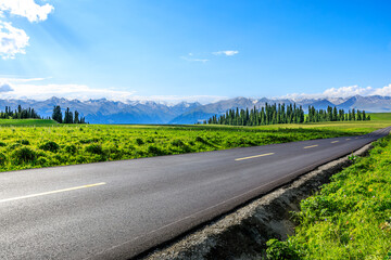 Country road and green meadow with mountain nature landscape under the blue sky