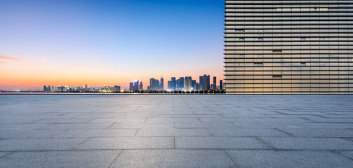 Empty square floor and glass wall with city skyline at dawn. Panoramic view.