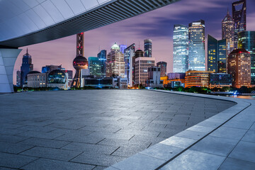 Empty square floor and pedestrian bridge with modern buildings at night in Shanghai