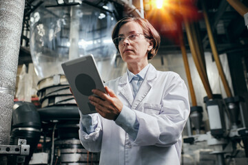 Proud female engineer with tablet working at the factory