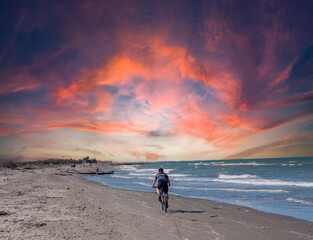 man rides a bicycle on the beach at sunset
