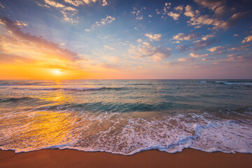 Ocean coastline, sunrise over the sea shore with splashing waves on the beach sand 