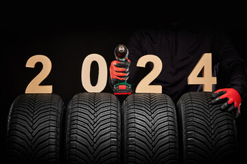 Car tires service and hands of mechanic with wheels screwdriver, 2024 happy new year background
