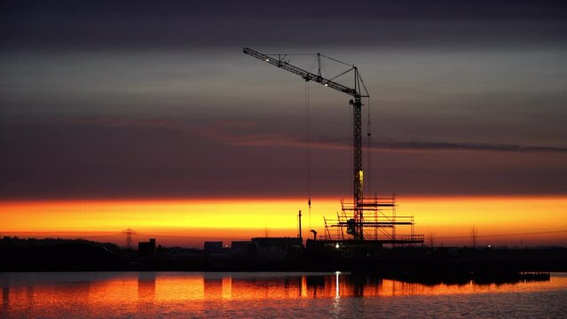 Construction of a new home with a crane during a very colorful dawn in Meerstad, Groningen.