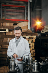 Engineer with tablet working at the factory surrounded with machinery