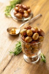 Spicy olives and rosemary twigs on a wooden table.