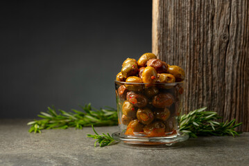 Spicy olives in a glass bowl on a stone table.