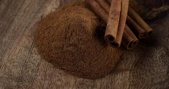 Heap of cinnamon sticks and cinnamon powder, rotation