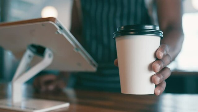 Cashier hands, coffee cup and counter for service, cafe order and offer in customer POV at point of sale. Waiter, barista or worker on digital technology for menu and giving drink or latte to person